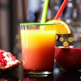 Chai Grenadine cạnh ly Tequila Sunrise và quả lựu