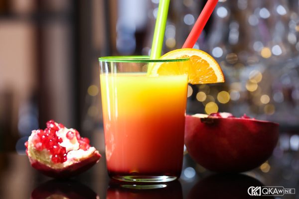 Chai Grenadine cạnh ly Tequila Sunrise và quả lựu