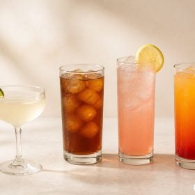 Bốn chai Monin Vanilla Caramel Rose và Grenadine cạnh cocktail