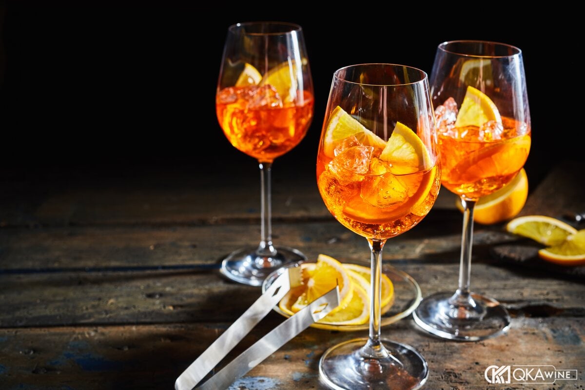 Ba ly spritz màu cam có đá và lát cam trên mặt gỗ
