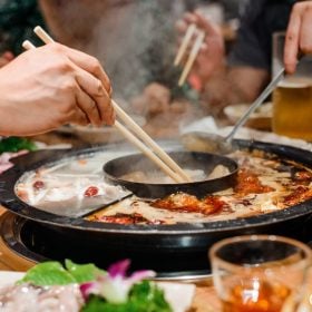 Bàn lẩu cay hai ngăn với cốc bia vàng bên cạnh
