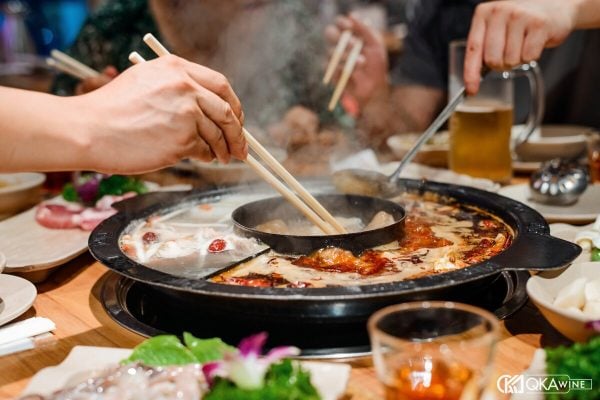 Bàn lẩu cay hai ngăn với cốc bia vàng bên cạnh