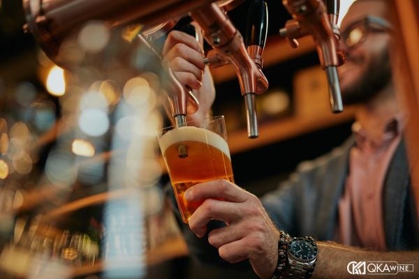 Bartender kéo cần rót bia tươi từ vòi vào ly tại quầy bar