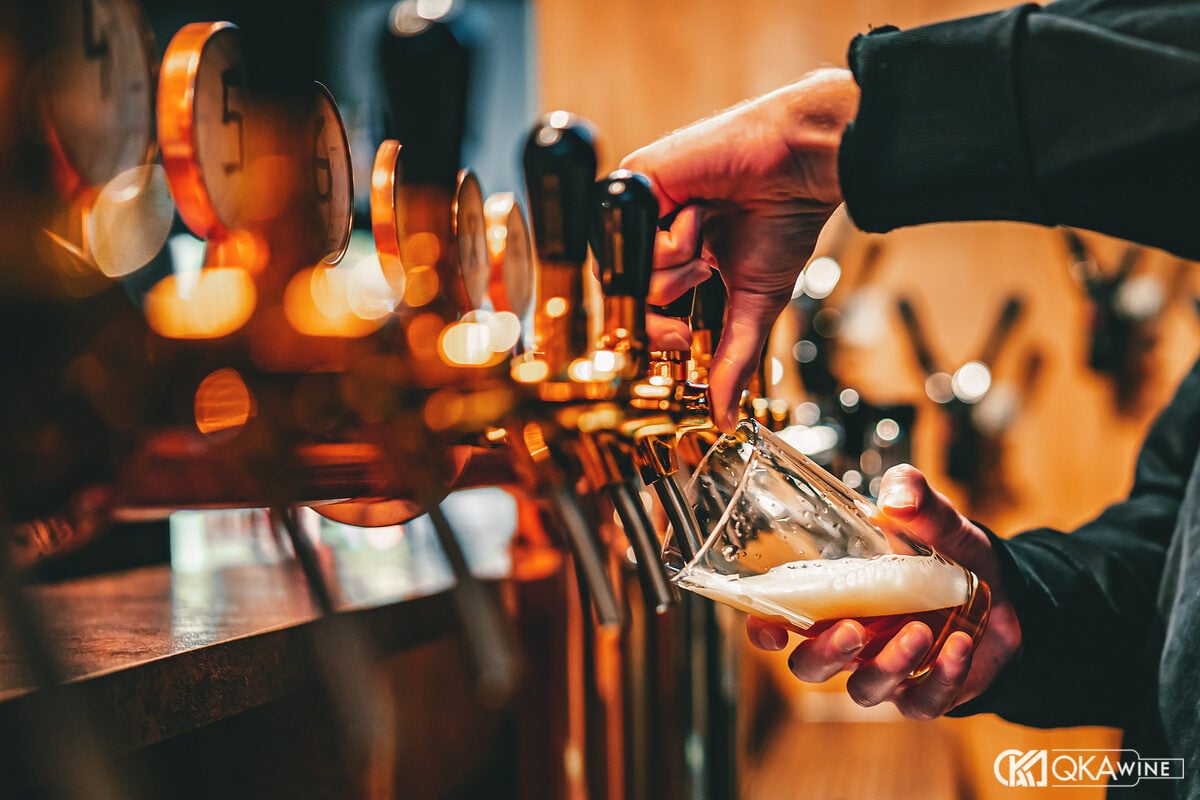 Bartender rót bia từ dãy vòi đồng tại quầy taproom
