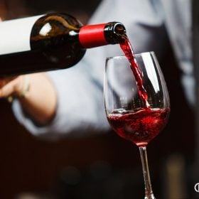 Cầm nửa dưới thân chai rót vang đỏ, miệng chai không chạm vành ly