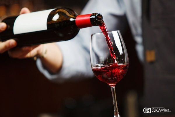 Cầm nửa dưới thân chai rót vang đỏ, miệng chai không chạm vành ly