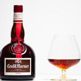 Chai Grand Marnier thắt ruy băng đỏ cạnh ly snifter