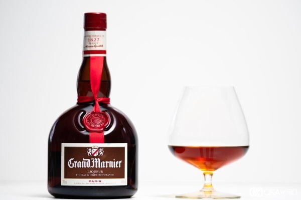 Chai Grand Marnier thắt ruy băng đỏ cạnh ly snifter