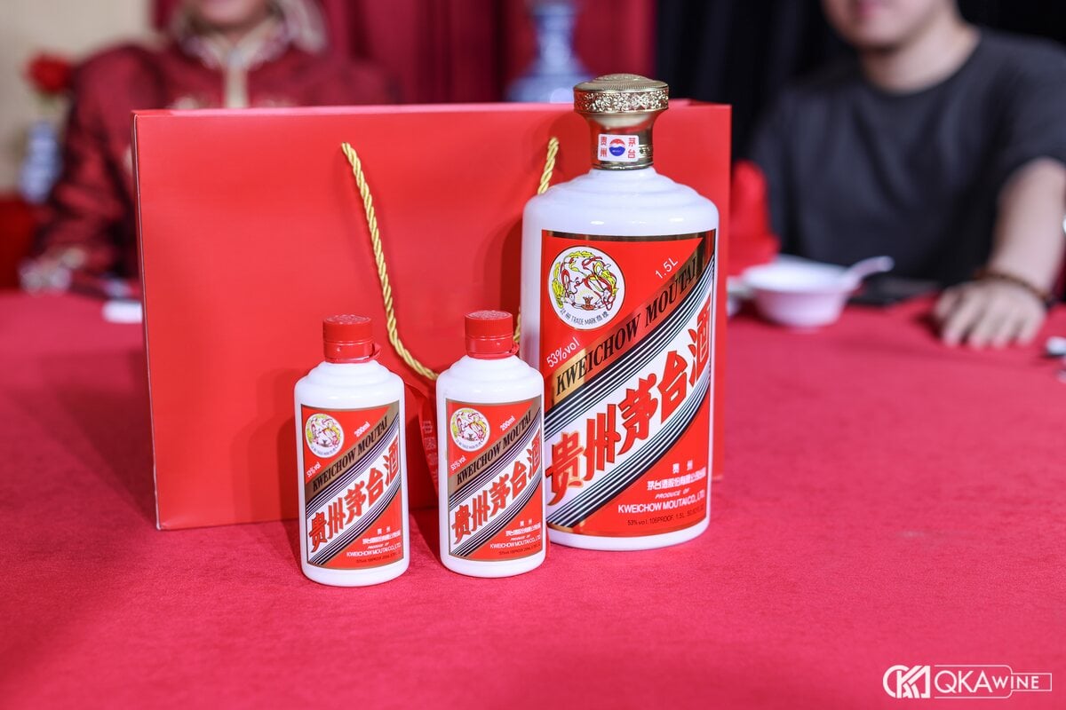 Chai Mao Đài và hai chai nhỏ đặt cạnh túi quà đỏ trên bàn tiệc