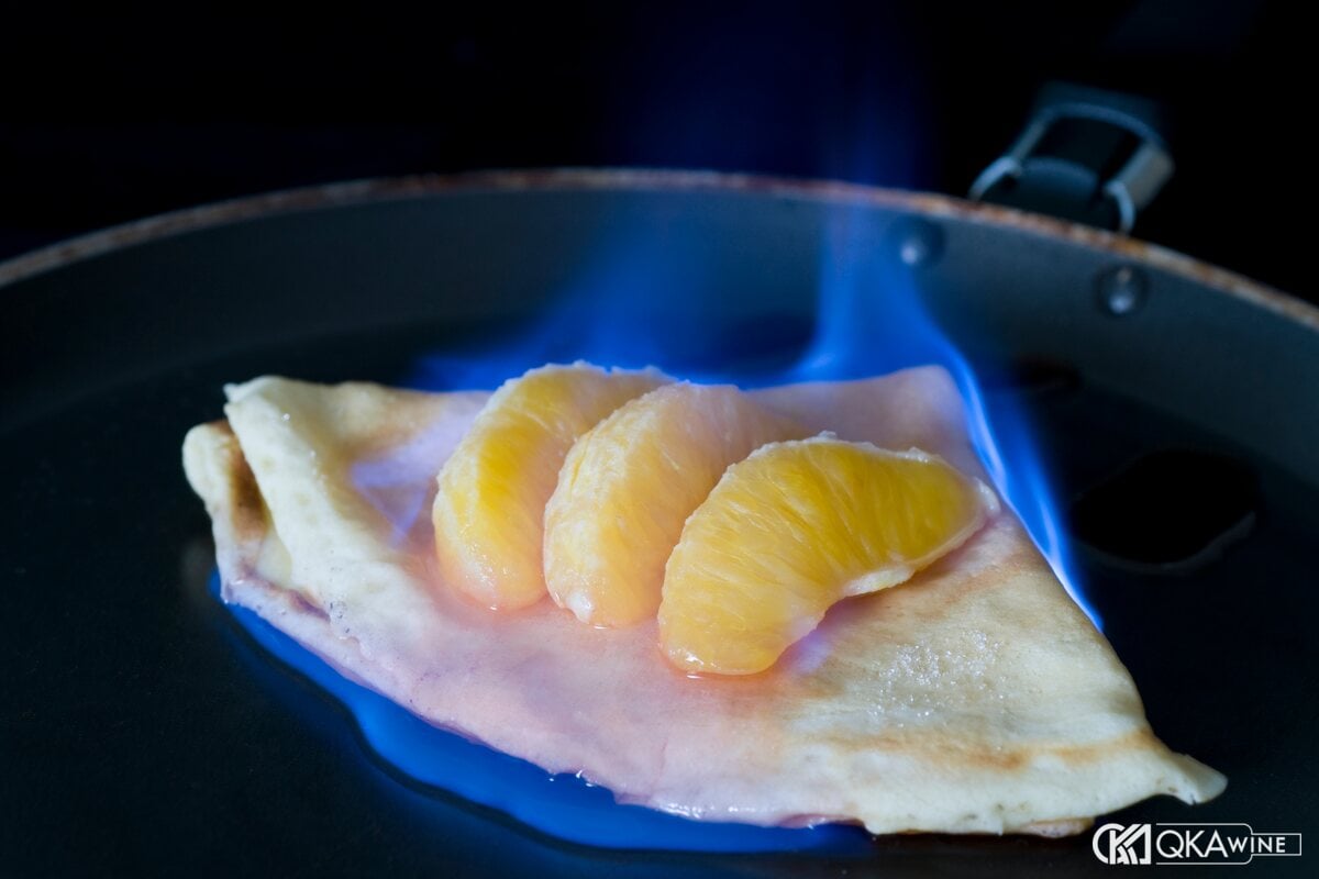 Bánh crêpe Suzette với múi cam đang cháy lửa xanh trong chảo