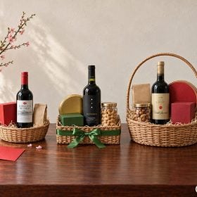 Giỏ quà tết 300k cạnh hai giỏ lớn hơn trên bàn gỗ