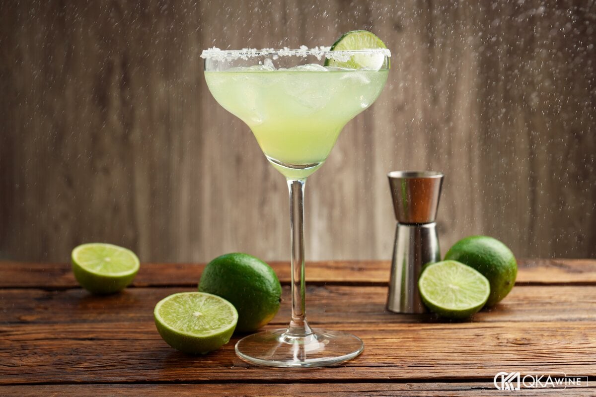 Ly Margarita viền muối cạnh những quả chanh xanh và jigger