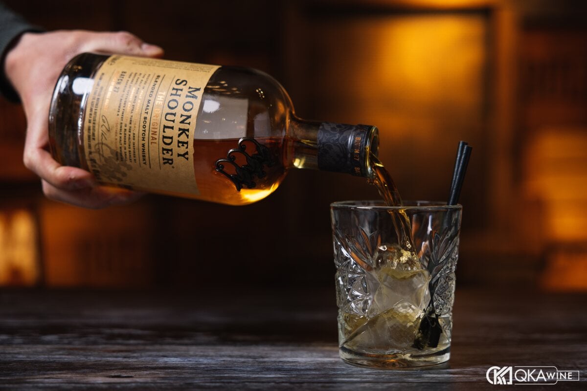 Rót Monkey Shoulder từ chai vào ly có đá tại quầy bar