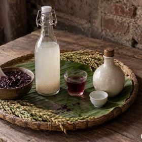 Bốn kiểu rượu nếp bày trong bát, chai và nậm trên mâm tre