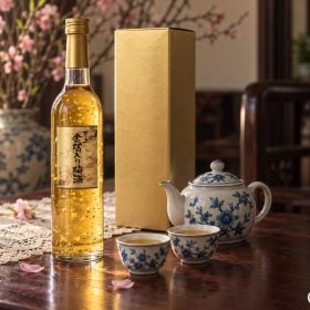 Chai rượu vảy vàng 500 ml cạnh hộp vàng trên bàn trà Tết