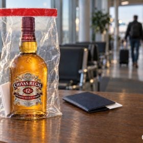 Chai rượu xách tay trong túi niêm phong cạnh hộ chiếu